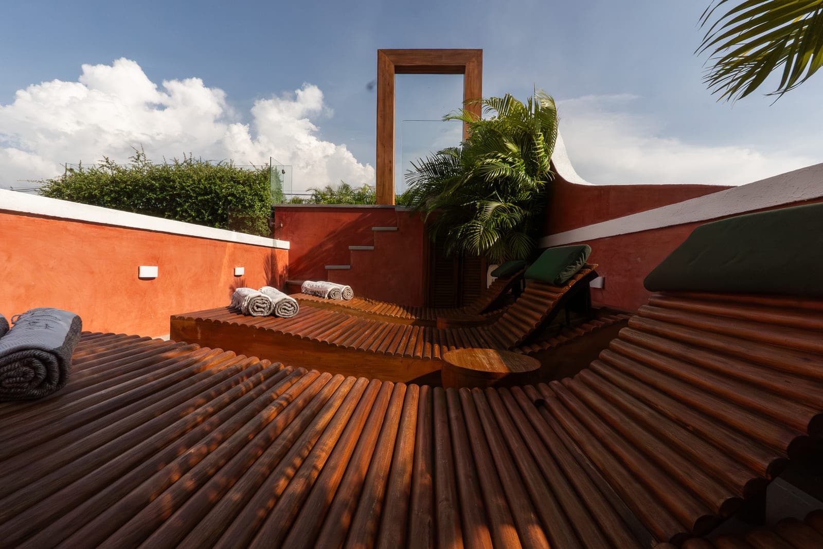 Deck de madera del rooftop junto al muro rojo